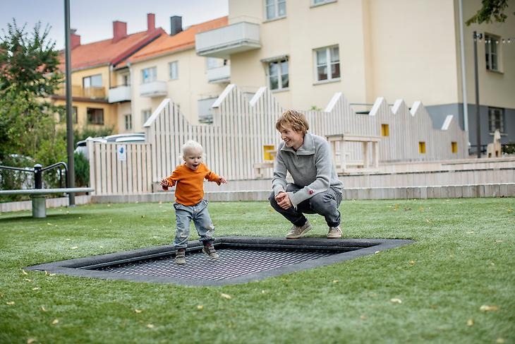 En pappa leker med sin dotter i Borgmästarängen i Sigtuna stad.