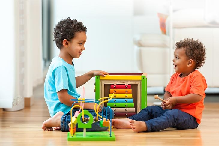 Två barn som sitter och leker med leksaker på en förskola inomhus.