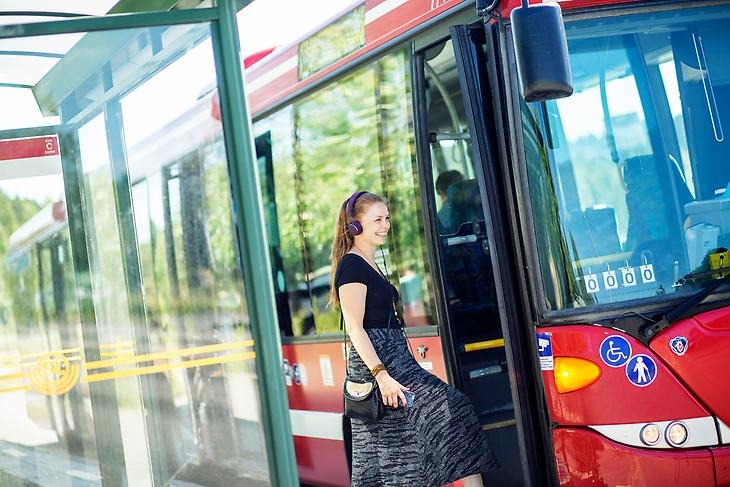En kvinna som kliver på en röd SL buss.