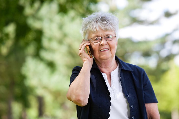 Äldre kvinna talar i mobiltelefonen.