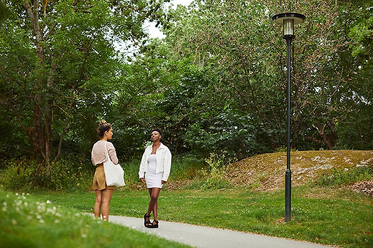 Två kvinnor på promenad i park.
