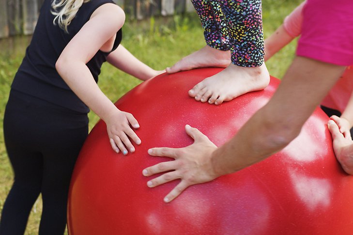 ett barn står på en röd, stor boll. Fler barn runtomkring.