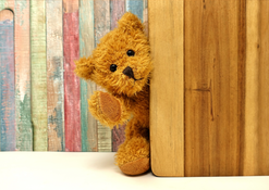 En teddybjörn kikar fram bakom en vägg